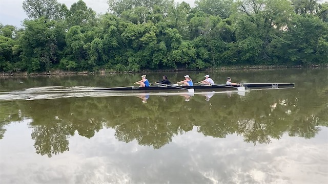 A group of women row a four oared boat up the Kansas River.